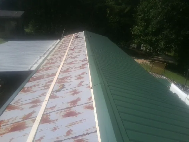 Old rusted panels beside newly installed green metal roofing — Wind Damage Roof Repair by Roofing Brothers in Kremmling