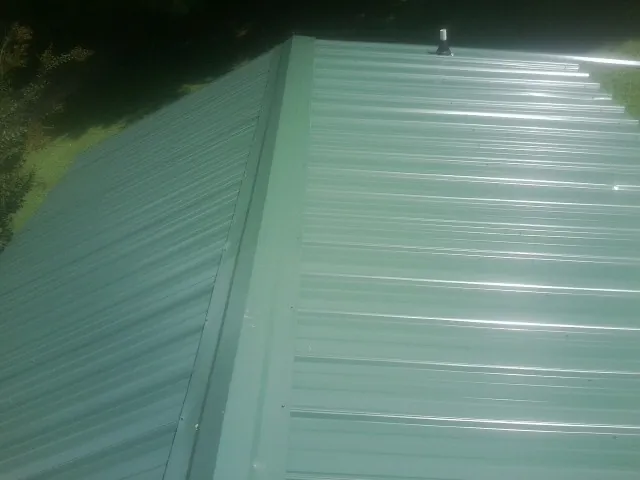 New green metal panels meeting at the ridge of a roof — Flat Roof Repair work by our crew in Kremmling