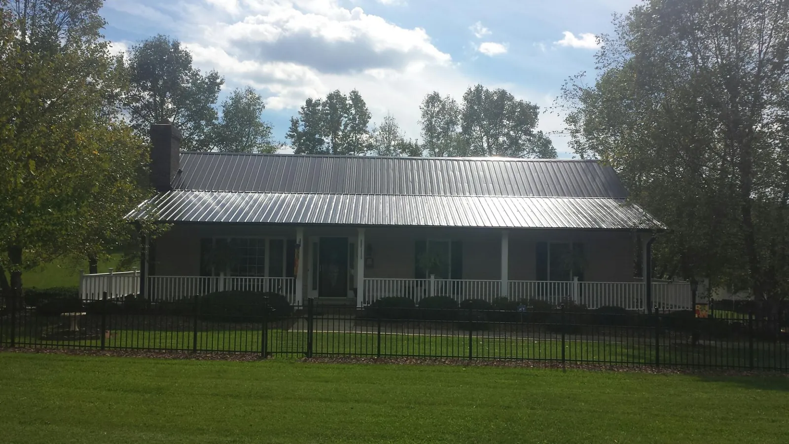 Gray metal roof on a brick ranch with a full width front porch — Gutter Guard Installation work by our crew in Kremmling
