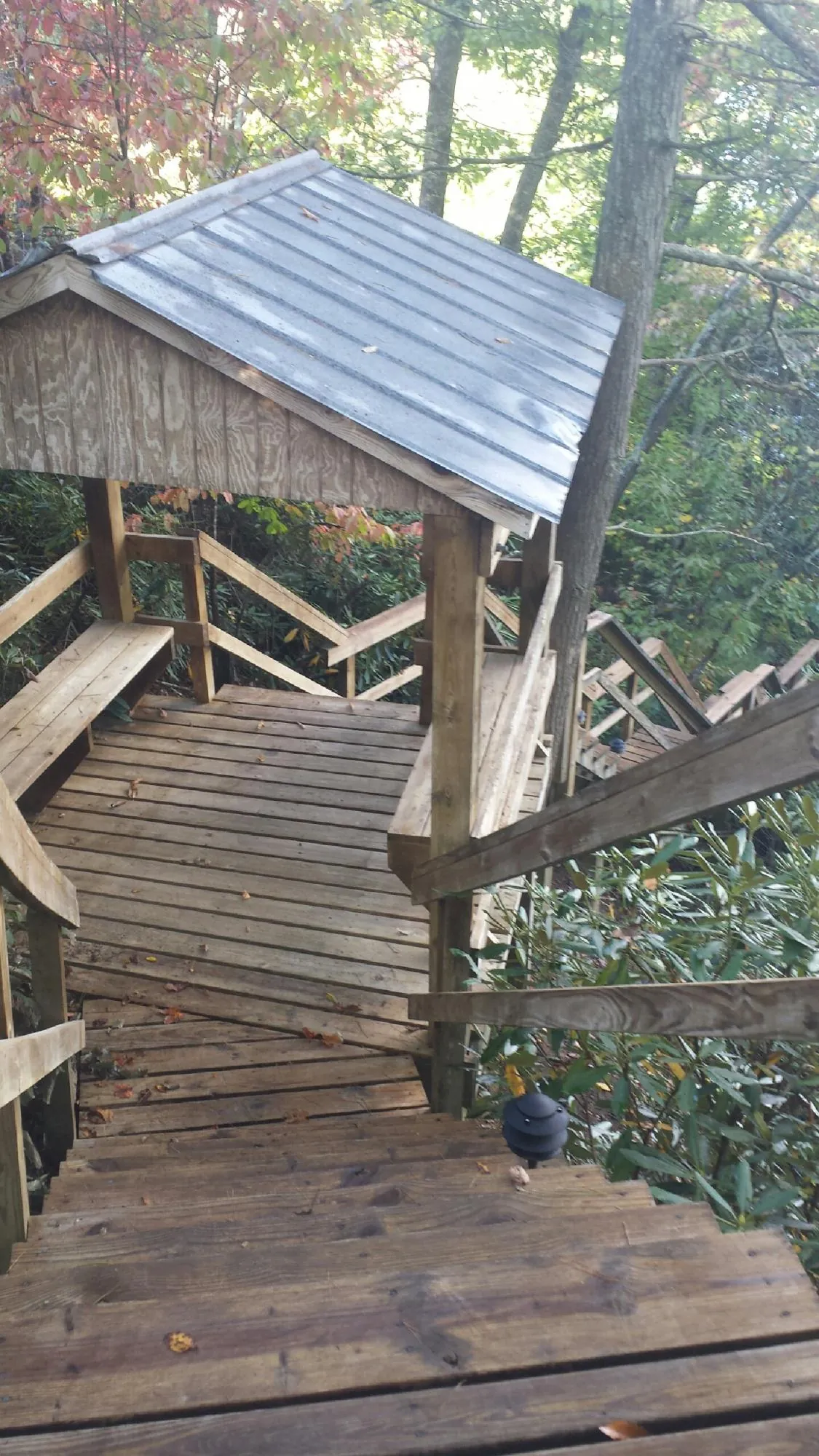 Metal roofed shelter over wooden steps on a wooded walkway — Skylight Repair & Installation work by our crew in Kremmling