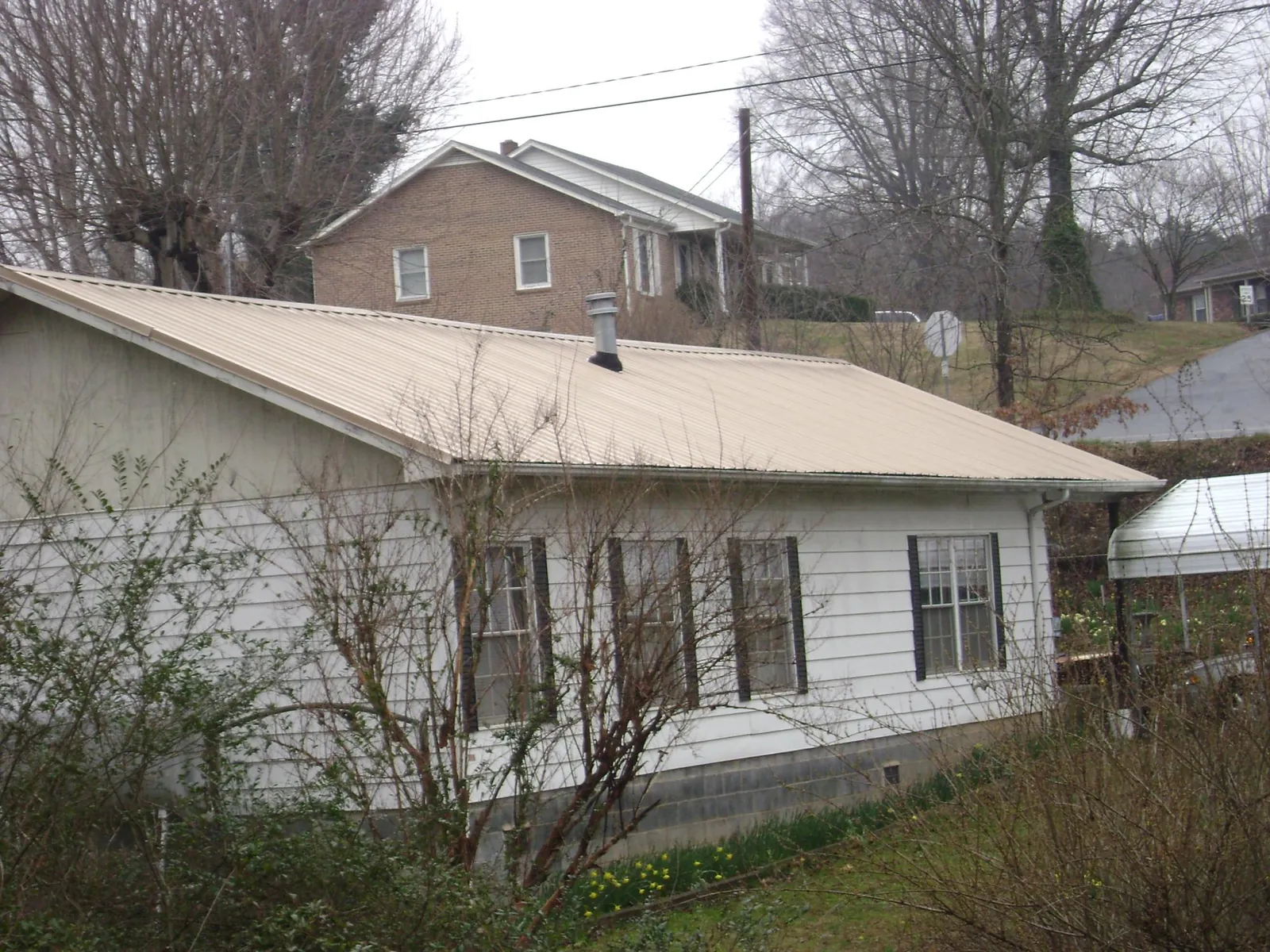 Tan metal roof on a white sided house set into a hillside — Commercial Roofing by Roofing Brothers in Kremmling