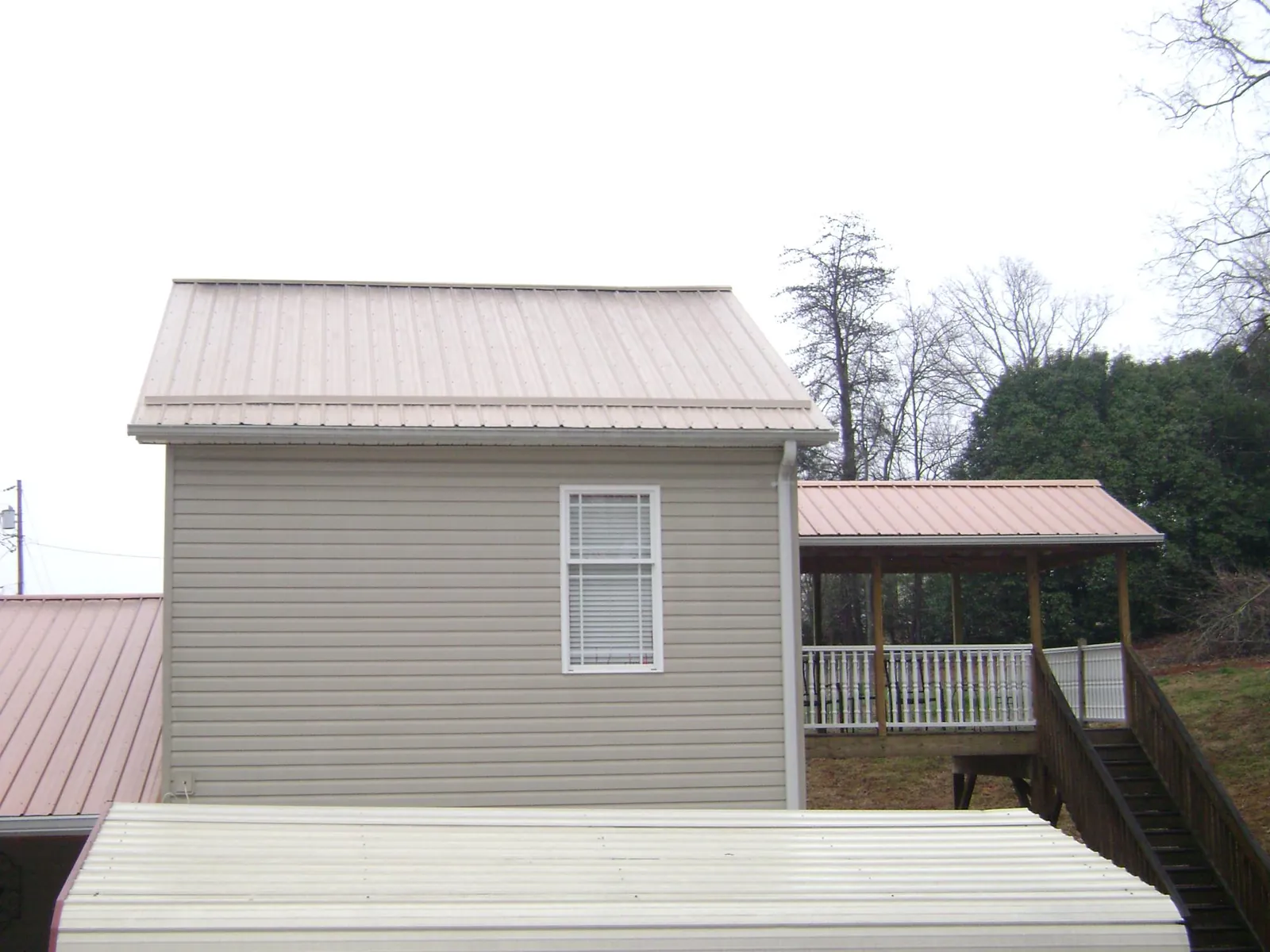 Tan metal roofs on a two story addition and attached porch, from a Roof Replacement job in Kremmling